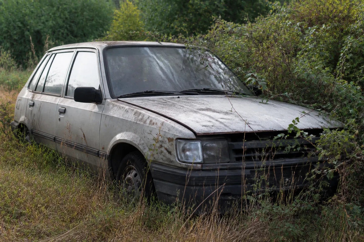 Voiture hors d&rsquo;usage laissée à l&rsquo;abandon sur un terrain envahi par la végétation
